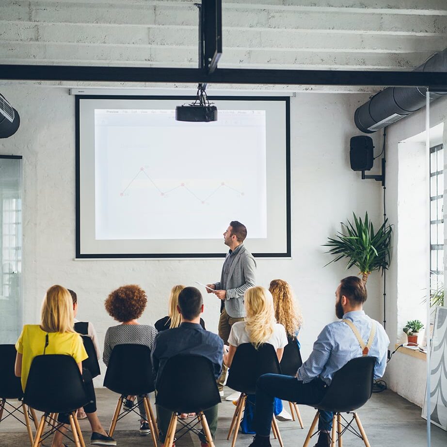 man presenting a slide to a group of business people.